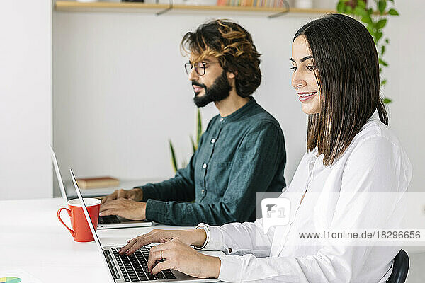 Smiling freelancer with colleague working at desk in office