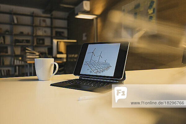 Tablet PC with solar panels and turbines on screen in office