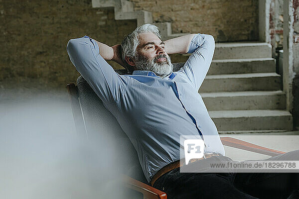 Thoughtful mature architect resting in chair at construction site