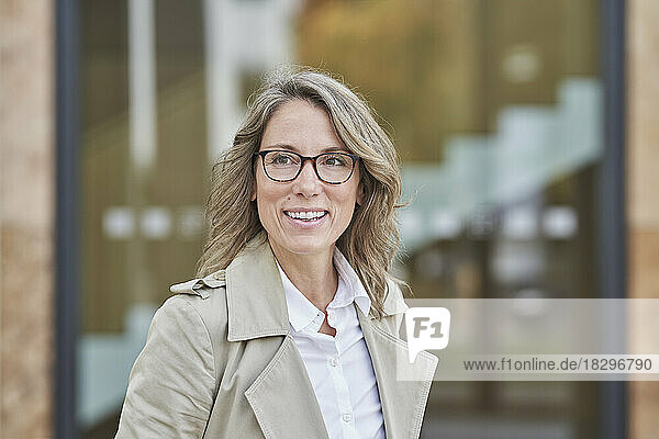 Happy mature businesswoman wearing eyeglasses outside building