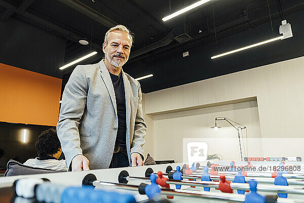 Smiling businessman playing foosball in office