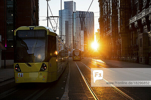 Großbritannien  England  Manchester  Seilbahnen fahren bei Sonnenuntergang entlang der Straße in der Innenstadt