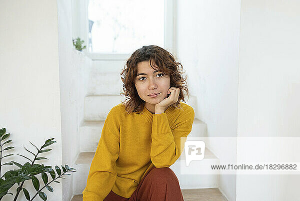 Young woman sitting on stairs at home