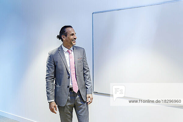 Happy businessman looking at whiteboard in conference room