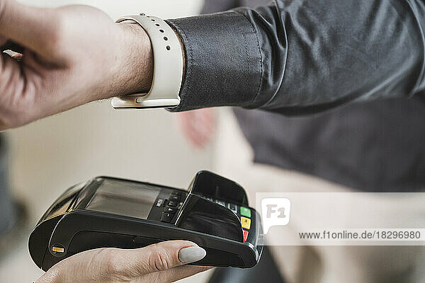 Hand of young businessman paying with smart watch