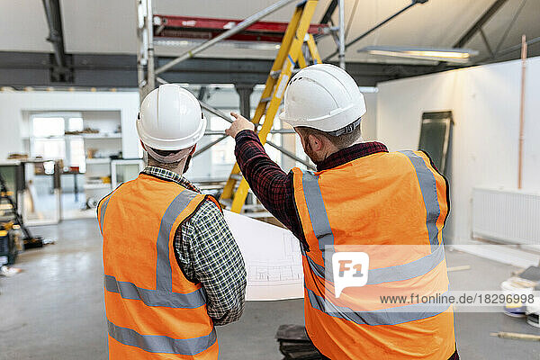 Engineers wearing hardhats examining and having discussion at site