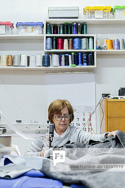 Woman sewing fabric in upholstery workshop