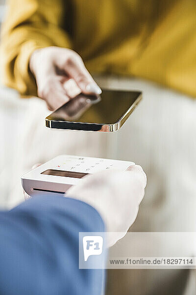 Hand of businesswoman paying through smart phone on credit card reader