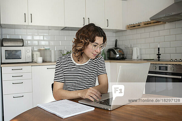 Freelancer using laptop on table in kitchen at home
