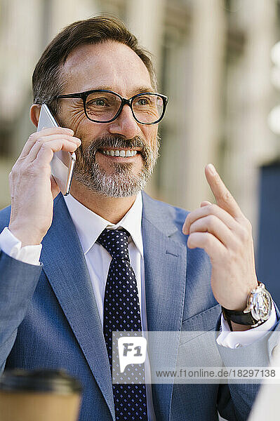 Glücklicher reifer Geschäftsmann mit Brille  der auf dem Handy spricht