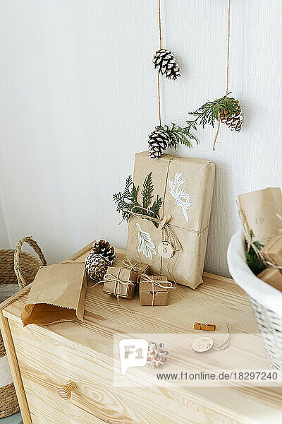 Christmas gift boxes with decorated pine cones kept on cabinet
