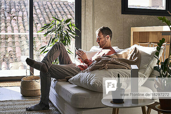 Man using mobile phone sitting on sofa at home