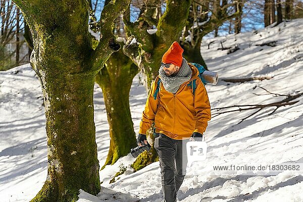 Fotograf beim Trekking mit Rucksack  der einen Buchenwald mit Schnee fotografiert  Spaß und Winterhobbys