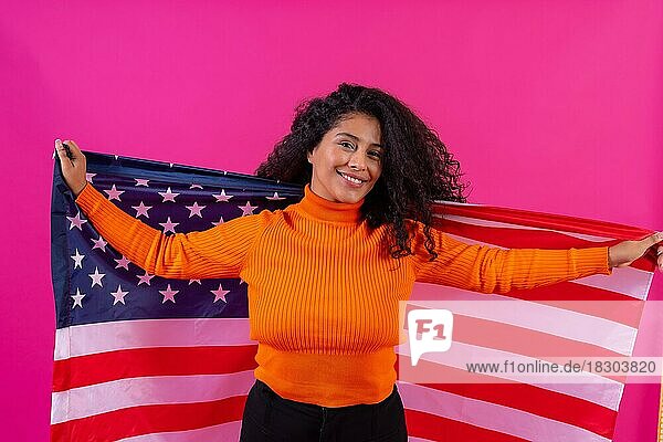 Lockenköpfige Frau lächelnd mit usa-Flagge auf rosa Hintergrund  Studioaufnahme
