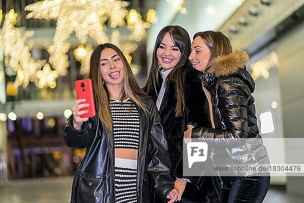 Christmas in the city at night  decoration in winter. Friends enjoying smiling taking a selfie