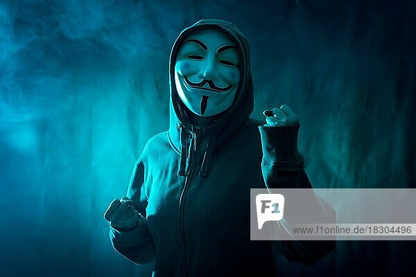 Hacker with anonymous mask with a symbol of fight  with a background of smoke and blue led