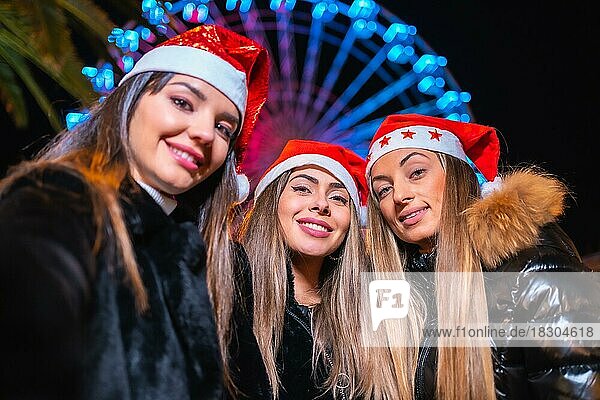 Weihnachten in der Stadt bei Nacht  Dekoration im Winter. Freunde auf einem beleuchteten Riesenrad machen ein Selfie