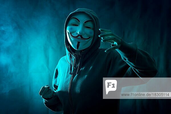 Hacker mit anonymen Maske mit einem Symbol des Kampfes  mit einem Hintergrund von Rauch und blau geführt