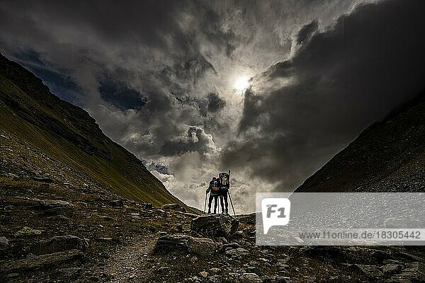 Val Minor mit Bergsteiger in herbstlichen Farben mit dramatischem Wolkenhimmel  St Moritz  Engadin  Graubünden  Schweiz  Europa