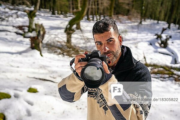 Fotograf  Mann  der ein Foto im Schnee macht  genießt die Winterfotografie in einem verschneiten Wald