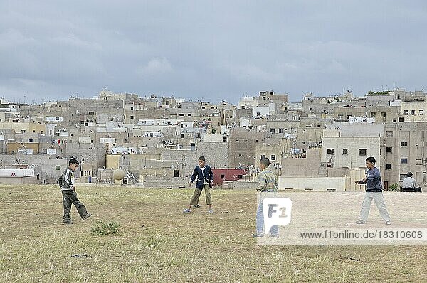 Jungs spielen Fußball  dahinter Häuser und Wohnungen der ärmeren Bevölkerung  Siedlung außerhalb von Fes  Marokko  Afrika