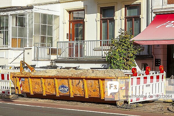 Orange Absetzmulde für Bauschutt auf der Straße stehend vor Wohngebäuden  Deutschland  Europa