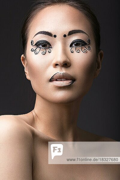 Schöne asiatische Mädchen mit einem kreativen Make-up  ungewöhnliche Wimpern Papier. Schönheit Gesicht. Bild im Studio auf einem schwarzen Hintergrund genommen