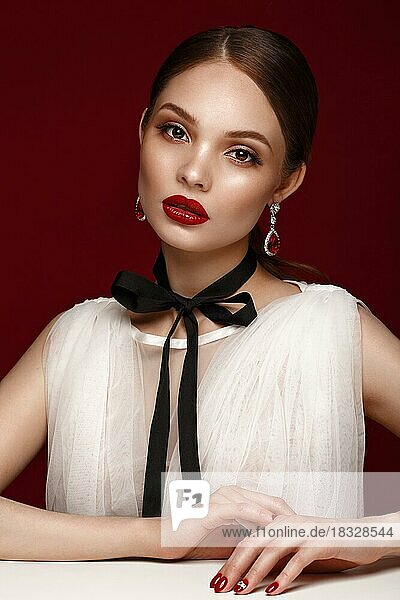 Schönes Mädchen im weißen Kleid mit klassischem Make-up und roter Maniküre. Schönes Gesicht. Foto im Studio aufgenommen