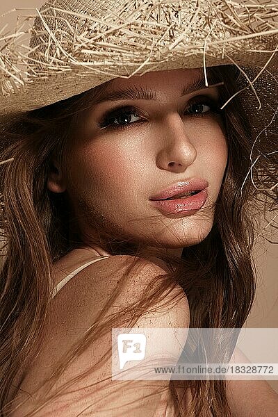 Porträt einer schönen Frau mit Strohhut  offenem Haar und nacktem Make-up. Schönheit Gesicht