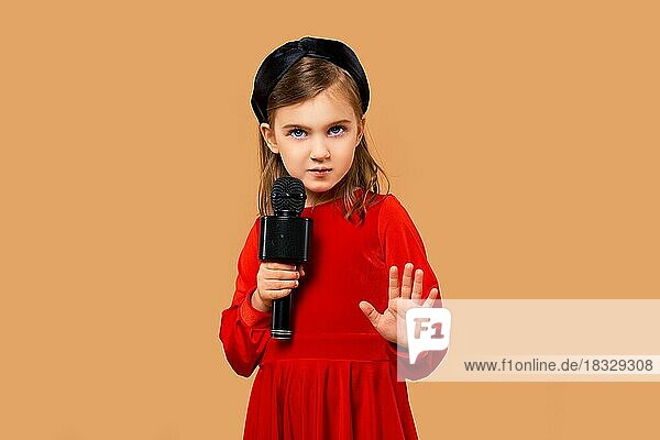 Künstlerisches Mädchen im roten Kleid singt in Karaoke-Mikrofon