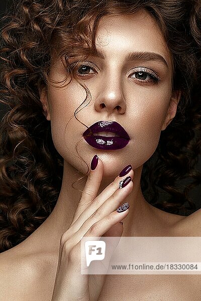 Beautiful girl with evening make-up  purple lips  curls and design manicure nails. beauty face. Photos shot in studio