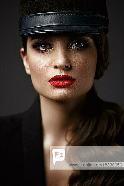 Schöne sexy Frau in einem modischen Hut  mit klassischem Make-up  Wellenhaar und roten Lippen. Schönes Gesicht. Foto im Studio aufgenommen