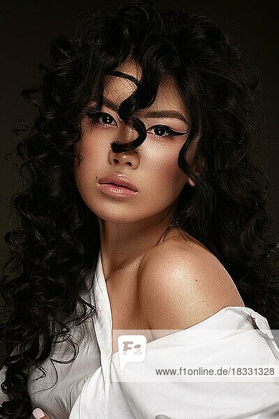 Schöne asiatische Frau in weißem Hemd  mit Make-up und Locken. Schönes Gesicht. Foto im Studio aufgenommen