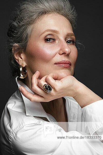 Porträt einer schönen älteren Frau im weißen Hemd mit klassischem Make-up und grauem Haar