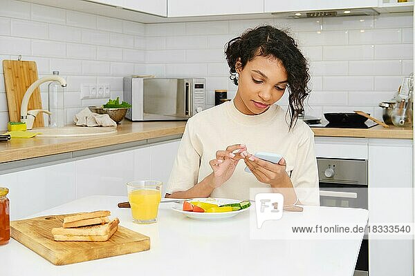 Junge afrikanische Frau liest morgens beim Frühstück eine Nachricht auf dem Handy