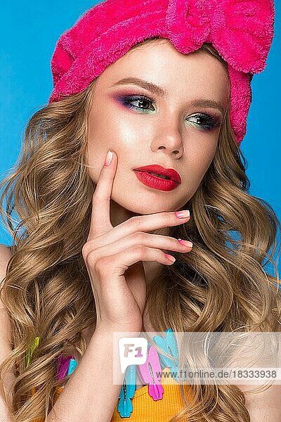 Helles  fröhliches Mädchen mit einem Hut  buntem Make-up  Locken und rosa Maniküre. Schönes Gesicht. Foto im Studio aufgenommen