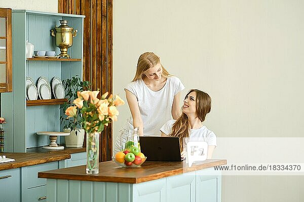 Zwei schöne Studentinnen machen eine Videokonferenz in der Küche