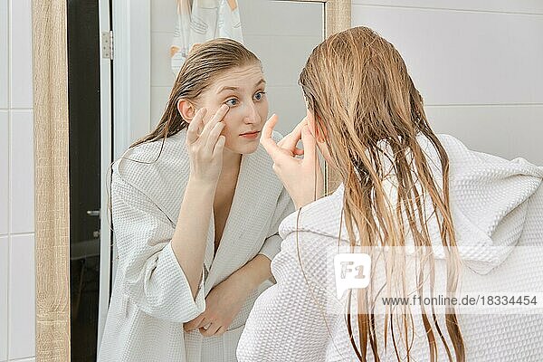 Junge Frau  die ihr Gesicht nach dem Duschen mit einer Creme eincremt