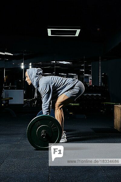 Muskulöser Mann beim Kreuzheben mit einer Langhantel im Fitnessstudio  Seitenansicht