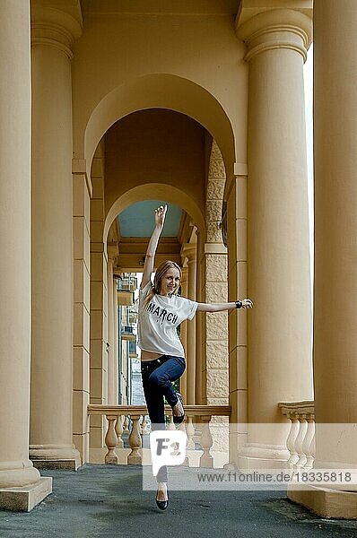 Weichzeichner-Foto eines springenden hübschen jungen Mädchens zwischen Säulen