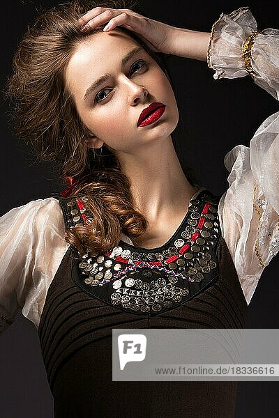 Schönes russisches Mädchen im Nationalkleid mit Zopffrisur und roten Lippen. Schönes Gesicht. Bild im Studio auf einem schwarzen Hintergrund genommen