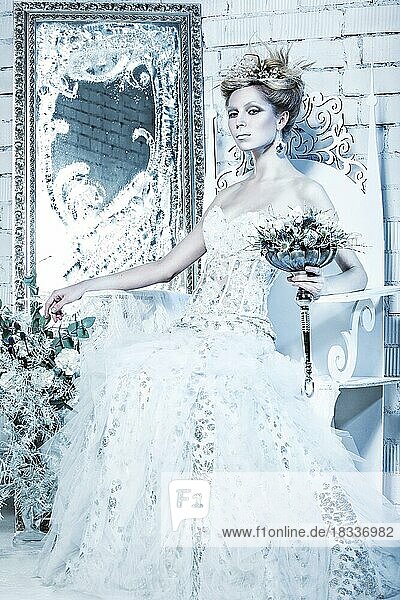Schönes Mädchen in weißem Kleid in das Bild der Schneekönigin mit einer Krone auf dem Kopf. Bild im Studio mit Dekorationen genommen