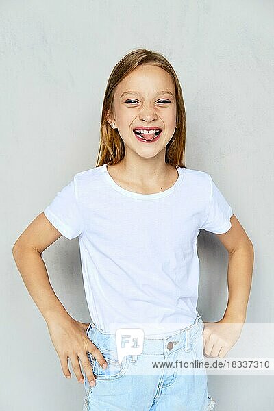 Young sportive girl in white t-shirt sticks out tongue