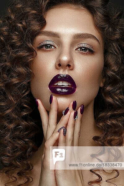 Beautiful girl with evening make-up  purple lips  curls and design manicure nails. beauty face. Photos shot in studio