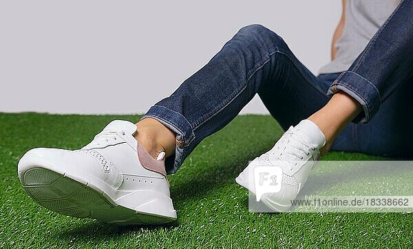Weibliche Beine in bequemen Freizeitschuhen auf dem Rasen. Kopieren Sie Spase Platz