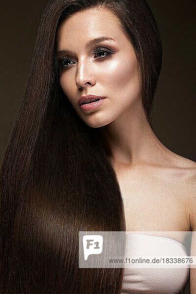 Beautiful brunette girl with a perfectly smooth hair  and classic make-up. Beauty face. Picture taken in the studio