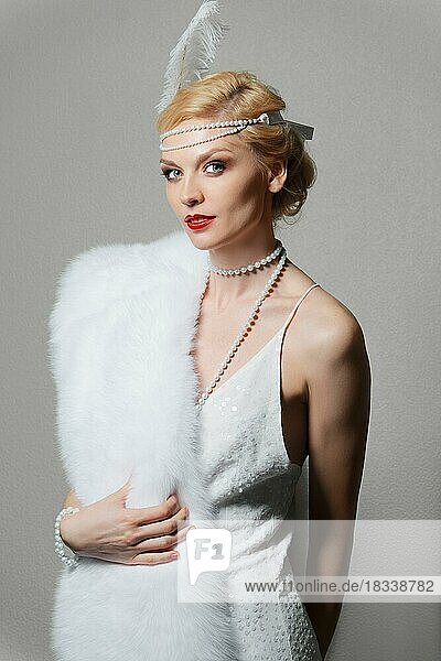 Retro style woman in white dress with shoulder straps and long fur stole. red lips  green eyes