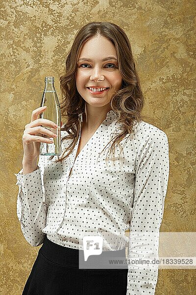 Porträt eines attraktiven lächelnden Mädchens mit einer Flasche Wasser in der Hand