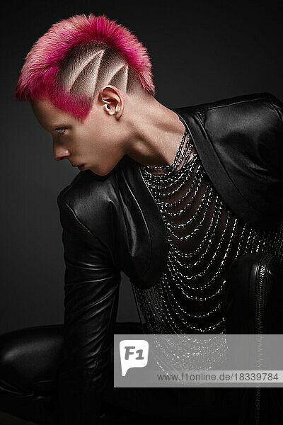 Junger Mann mit rosa Haaren und kreativem Make-up in Kunstkleidung. Foto im Atelier aufgenommen