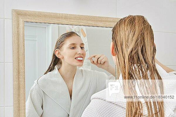 Young woman brushes her teeth in the bathroom before going to sleep